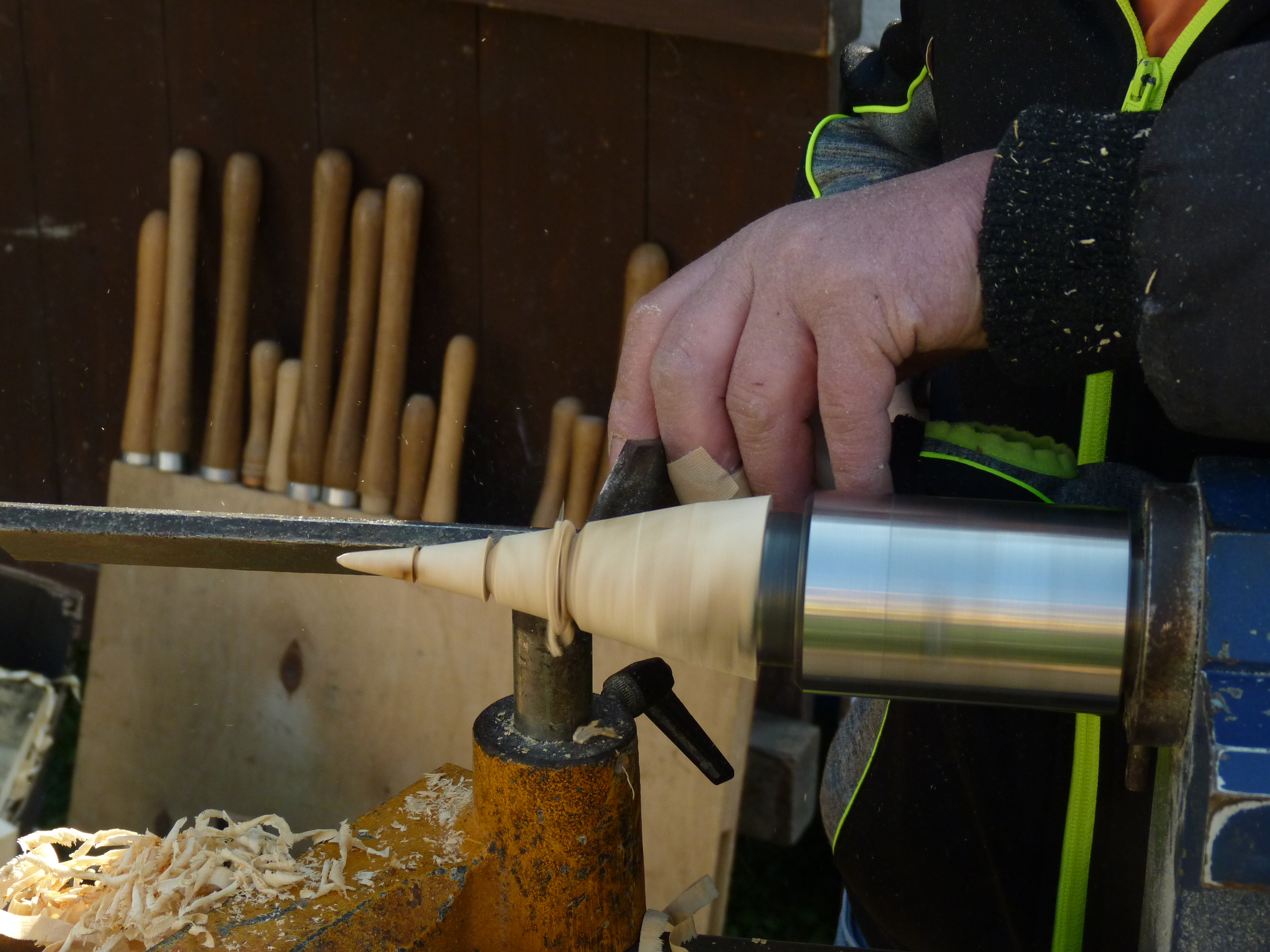 Ein Holzkegel wird gedrechselt. Daneben liegen Holzspäne.